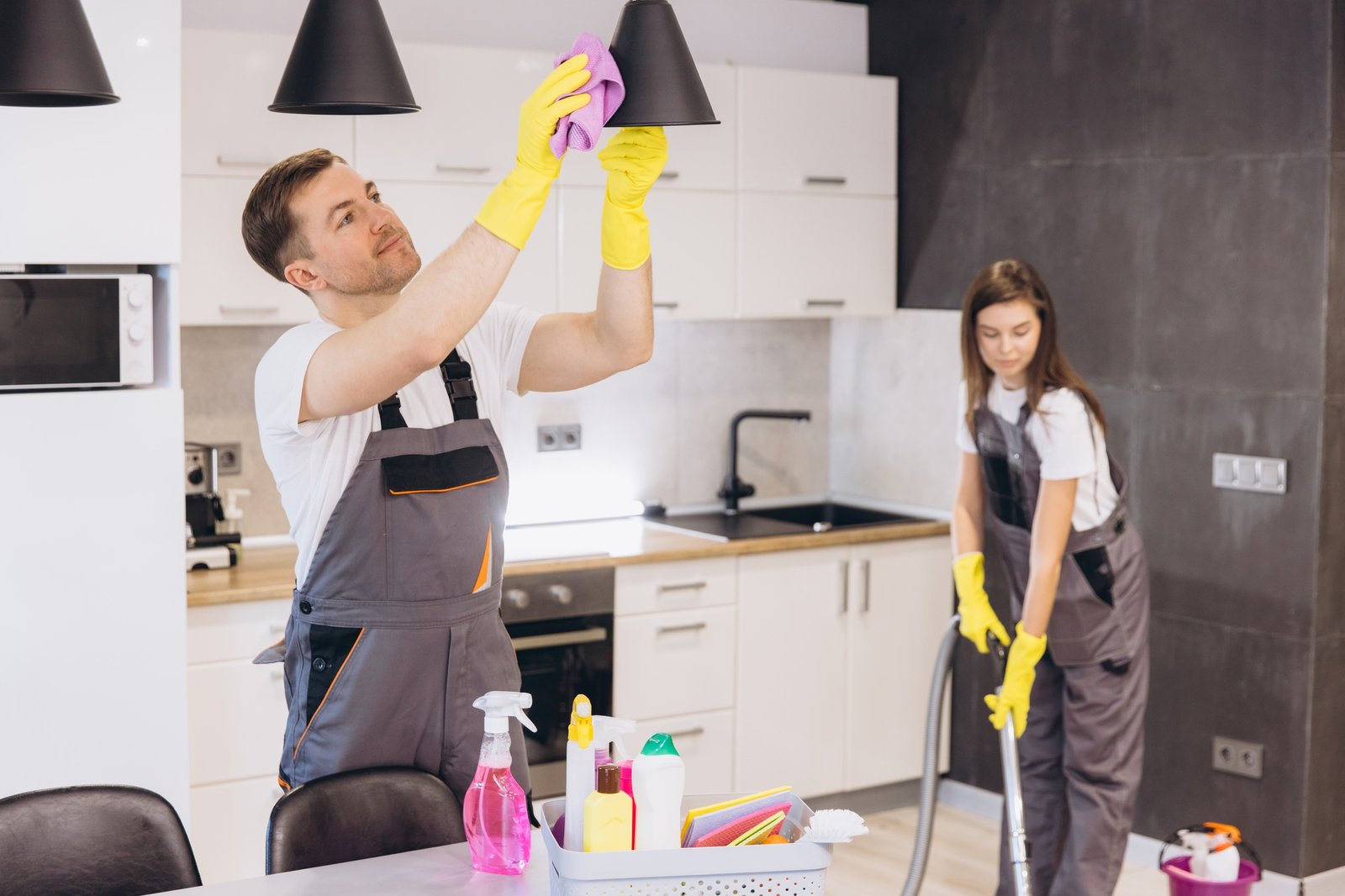 Cleaning company employees cleaning kitchen appliances and floor